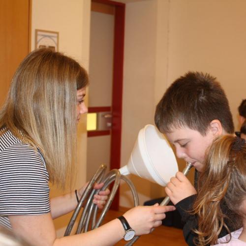 Kinder blasen in Mundstücke verschiedener Instrumente.