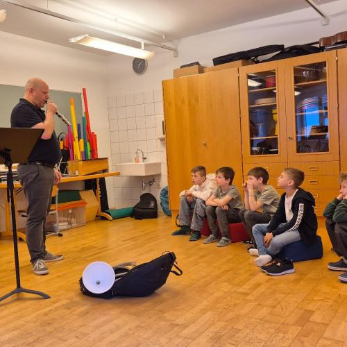 Ein Musikschullehrer erklärt den Kindern Instrumente.
