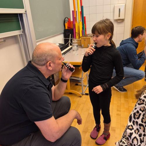 Lehrer und Kind probieren Mundstücke von Instrumenten aus.