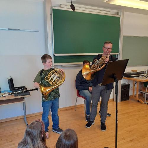 Ein Lehrer und sein Schüler spielen auf ihren Blasinstrumenten vor.