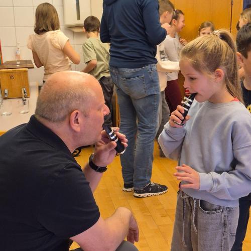 Lehrer und Kind probieren Mundstücke von Instrumenten aus.