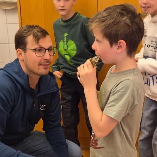 Lehrer und Kind probieren Mundstücke von Instrumenten aus.