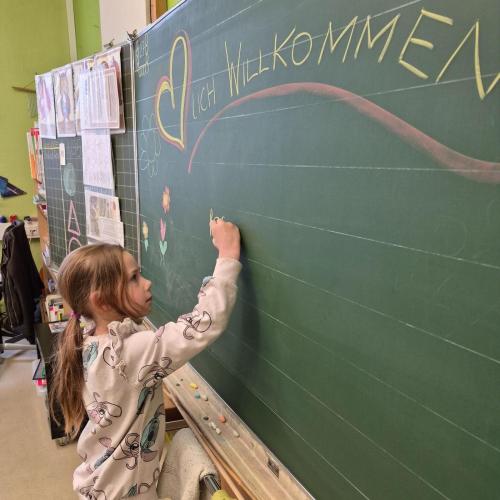 Kindergartenkind schreibt seinen Namen an die Tafel in der Schule