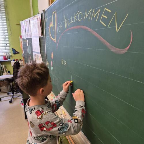 Kindergartenkind schreibt seinen Namen an die Tafel in der Schule