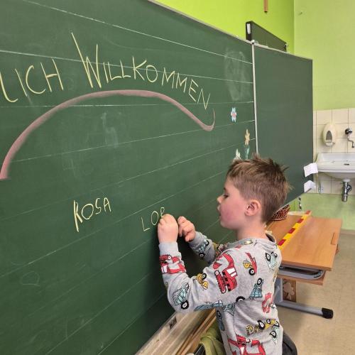 Kindergartenkind schreibt seinen Namen an die Tafel in der Schule