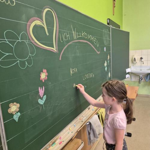Kindergartenkind schreibt seinen Namen an die Tafel in der Schule