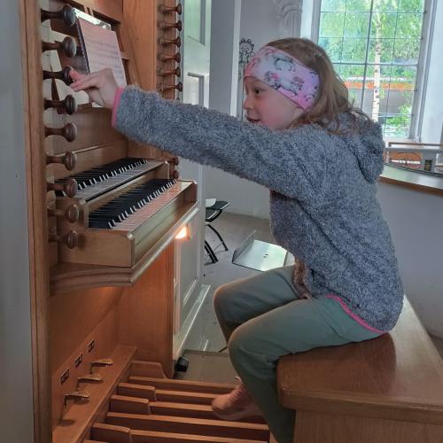 Kinder sitzen auf der Orgelbank und dürfen Orgel spielen.