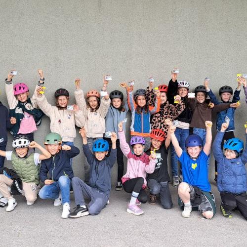 Die Kinder nach der erfolgreiche bestandenen Radfahrprüfung mit ihren Ausweisen und den Prüfern - Polizistenteam.