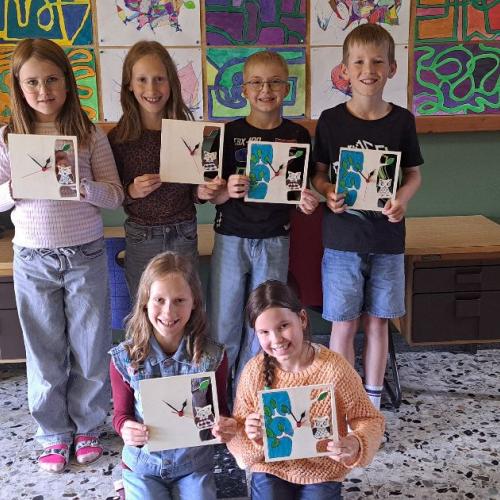 Die Kinder zeigen ihre selbst ausgesägten Wanduhren.