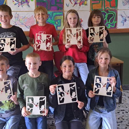 Die Kinder zeigen ihre selbst ausgesägten Wanduhren.