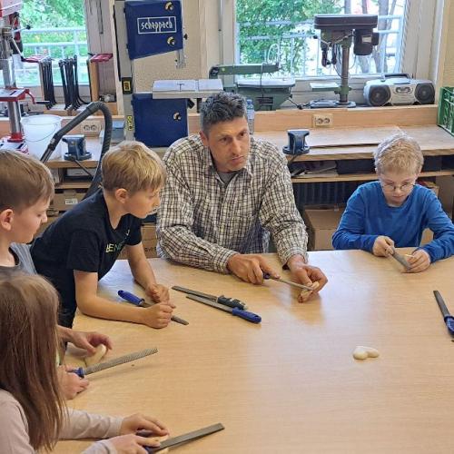 Der Referent vom TKS erklärt den Kindern den Umgang mit Werkzeug für Holz.