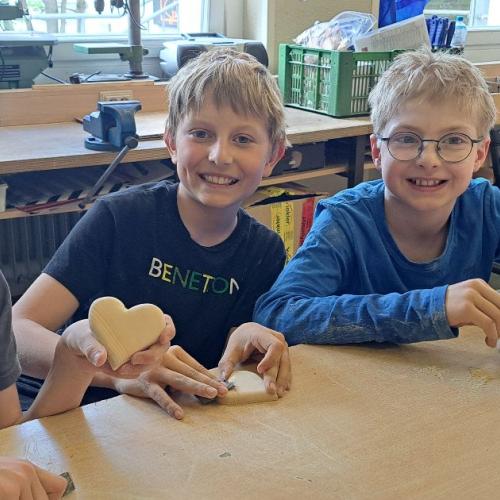 Kinder mit ihren Werkstücken aus Holz - Herzen