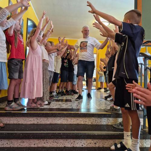 Schulwart Tom wird durch ein Spalier der Schulkinder durch das Schulhaus verabschiedet.