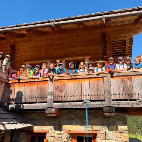 Die Kinder stehen am Balkon der Hütte.