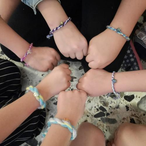 Die Kinder zeigen ihre Armbänder mit Herzanhänger.