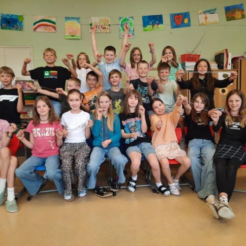 Die Kinder zeigen ihre Armbänder mit Herzanhänger.