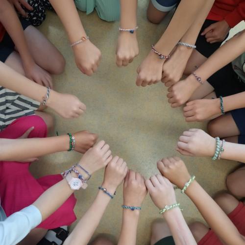 Die Kinder zeigen ihre Armbänder mit Herzanhänger.