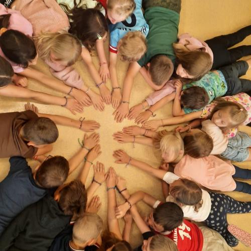 Die Kinder zeigen ihre Armbänder mit Herzanhänger.