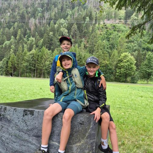 3 Kinder der 3a sitzen auf einem Stein.