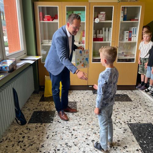 Der Bankbeamte der Raika gratuliert den Siegern zum Zeichenwettbewerb.