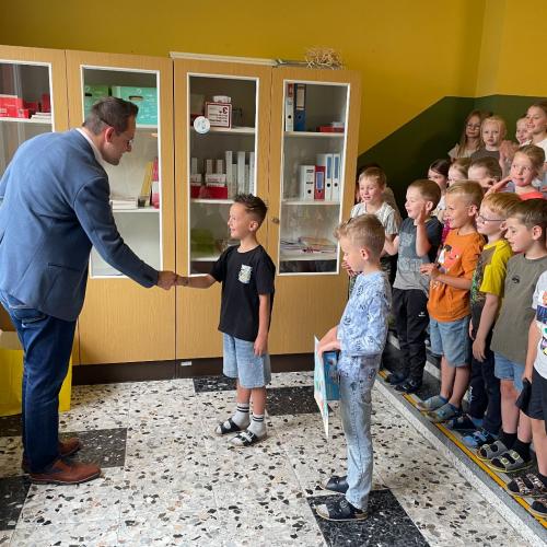 Der Bankbeamte der Raika gratuliert den Siegern zum Zeichenwettbewerb.