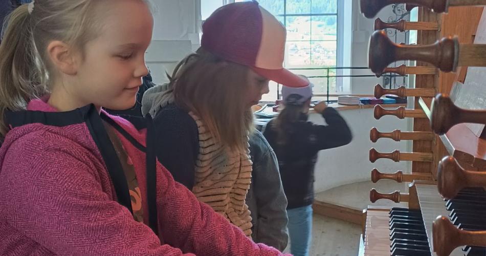 Kinder sitzen auf der Orgelbank und dürfen Orgel spielen.