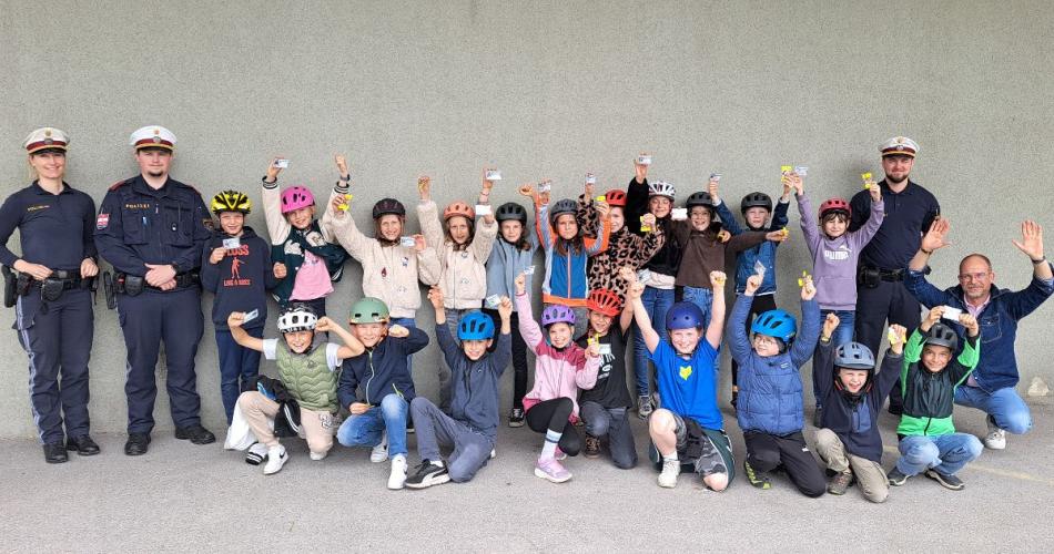 Die Kinder nach der erfolgreiche bestandenen Radfahrprüfung mit ihren Ausweisen und den Prüfern - Polizistenteam.