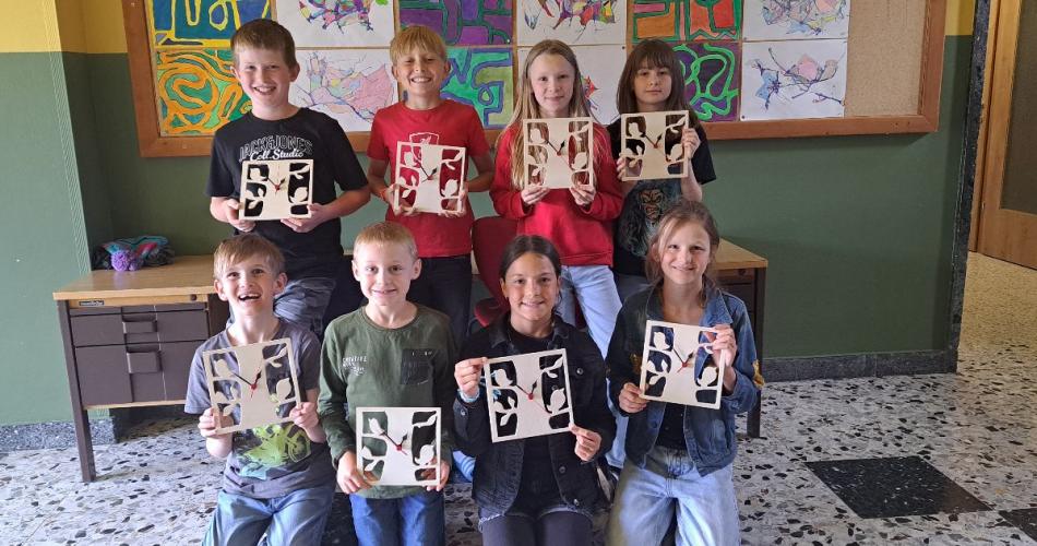 Die Kinder zeigen ihre selbst ausgesägten Wanduhren.
