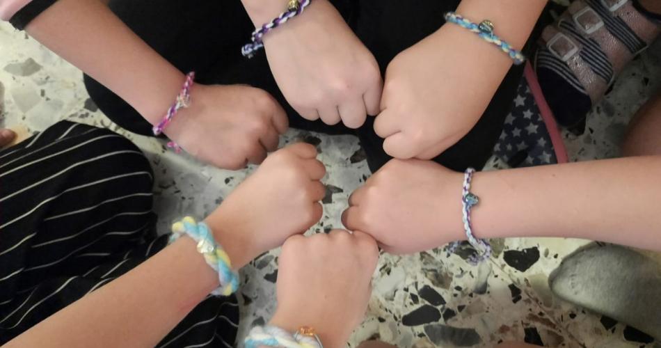 Die Kinder zeigen ihre Armbänder mit Herzanhänger.