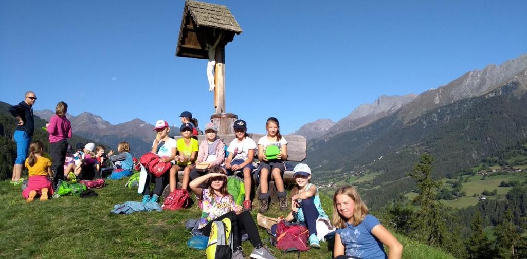 Kinder sitzen vor Kreuz